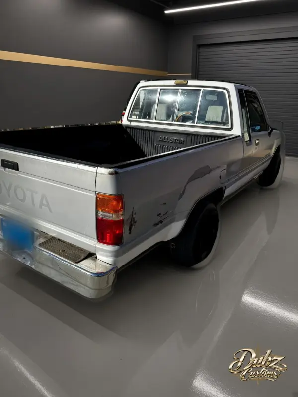 White 1991 Toyota pickup with dents and scrapes along the bed