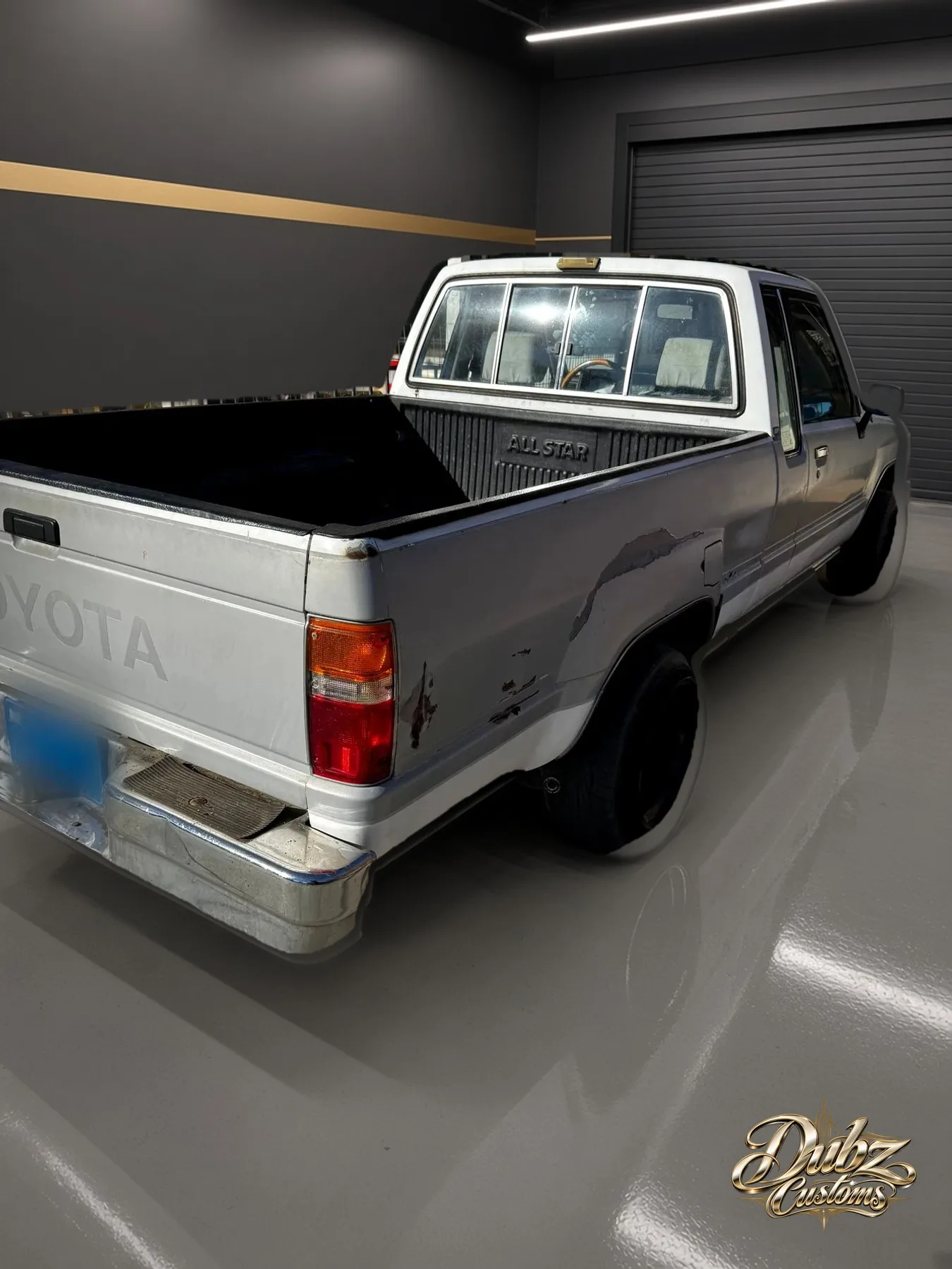 White 1991 Toyota pickup with dents and scrapes along the bed