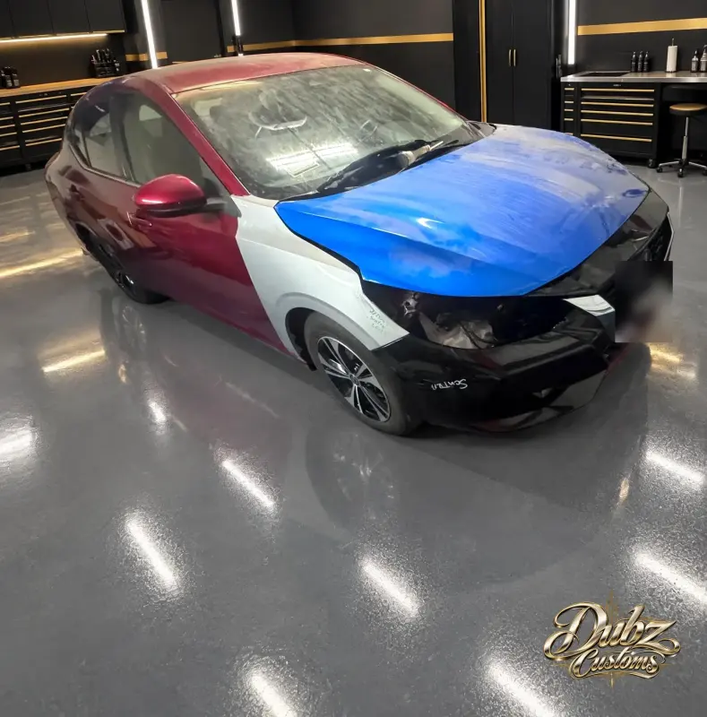 Nissan mid-repair with a new hood fitted and front parts removed